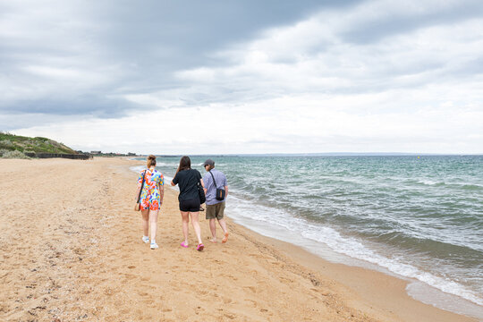 Fiends walk leisurely along sandy, scenic coast in Australia