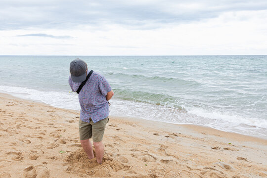 Man enjoying solitude on beach with feet buried in sand in Australia