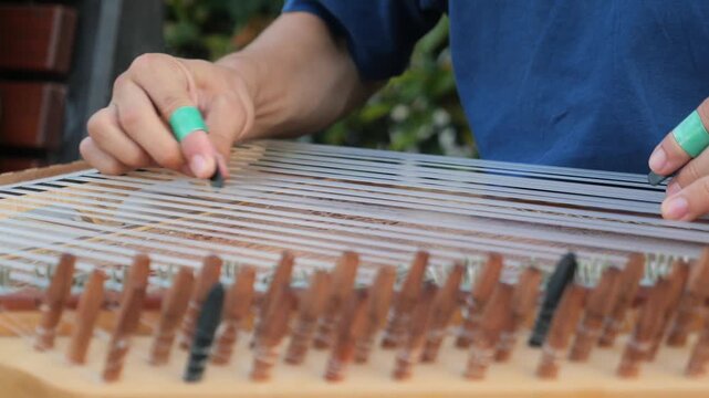 Close up view of man hands playing qanun traditional arabic musical instrument with finger picks during outdoor performance