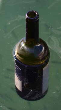 Glass bottle contaminating water, symbolizing pollution and environmental damage