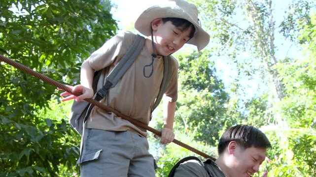 Asian Father and Son Crossing Suspension Bridge in Tropical Jungle