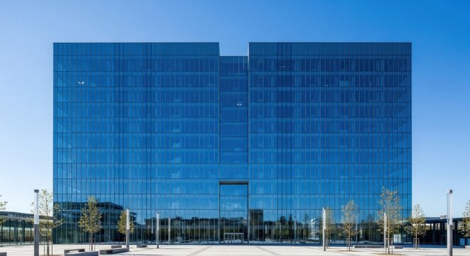 A modern glass office building with a blue sky in the background.