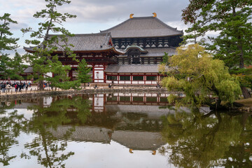 Naklejka premium Great Buddha Hall and the Todai-ji Chumon (Central Gate) of the Todai-ji Buddhist Temple with the reflection in the Todaiji Kagami-ike Pond on a cloudy autumn day, Nara, Japan