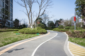 Curved asphalt pedestrian path beside green belt in residential community on a sunny day