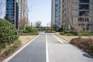 Obraz premium Asphalt pedestrian pathway in modern residential community flanked by greenery and high-rise buildings