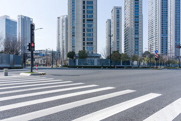 Empty pedestrian crossing at urban intersection with modern high-rise buildings under clear daylight © zhu difeng