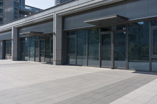 Modern commercial street with vacant glass-fronted storefronts and clean pavement under daylight
