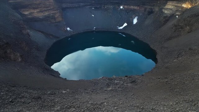 Aerial view of a crater lake surrounded by rugged terrain and rocky landscape
