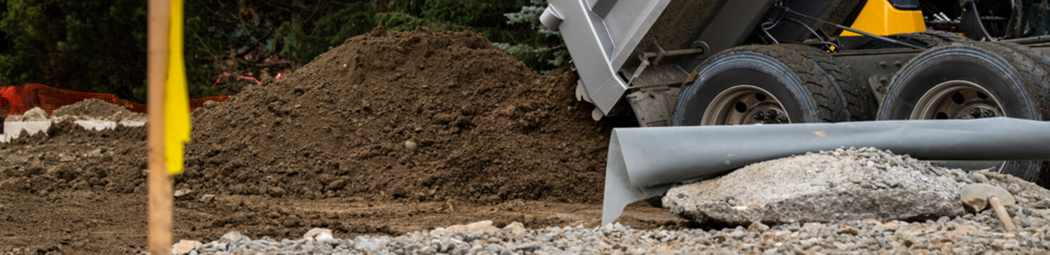 Dump truck delivering clean dirt, mineral soil, to a construction job site, hydraulic lift bed raising up
