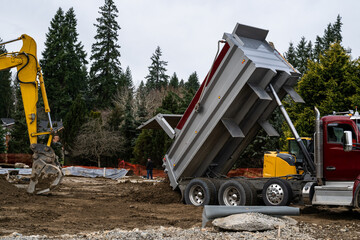 Dump truck delivering clean dirt, mineral soil, to a construction job site, hydraulic lift bed raising up  © knelson20