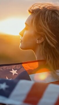 Attractive young American woman patriot wrapped in american flag at scenic sunset with sun flares. Concept of love to your country