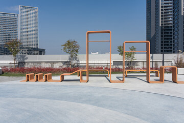 Orange geometric art installation in an urban plaza with modern architecture and clear blue sky © zhu difeng
