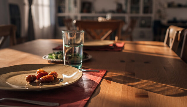 Prepared Iftar dining table setting with empty plates and water glass with copy space