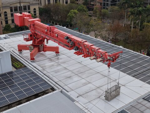 A red building maintenance unit BMU crane on a skyscraper roof.