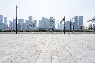 Fototapeta premium Empty urban plaza with paved ground and modern high-rise buildings in the background