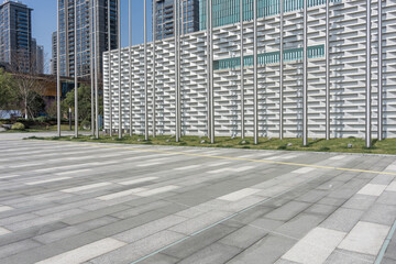 Modern urban plaza with gray paving stones and facade building featuring metal grilles © zhu difeng