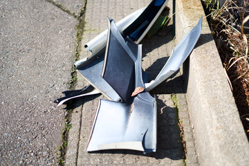 Broken plastic car bumper parts on sidewalk