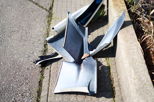 Broken plastic car bumper parts on sidewalk