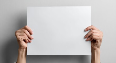 Close-up of two hands holding a blank white paper against a neutral gray background