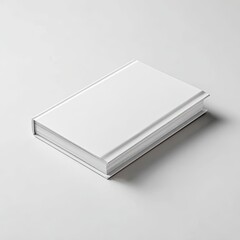 A closed, blank hardback book on a white surface, angled with shadows