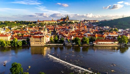Obraz premium Aerial view of an old city with red rooftops along river at sunset with castle in background