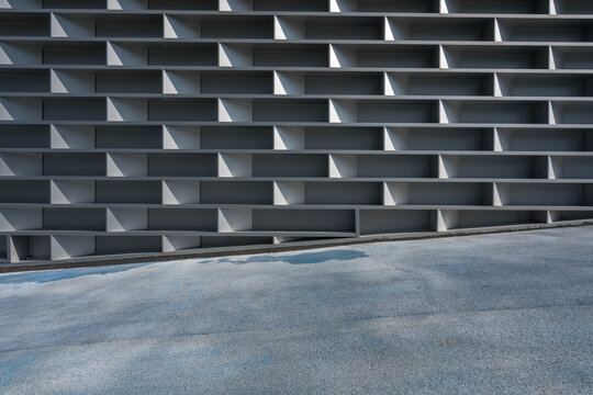 Gray geometric louvered wall with asphalt pavement in urban architectural setting