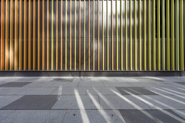Metal vertical slat facade casting light and shadow on paved ground surface © zhu difeng