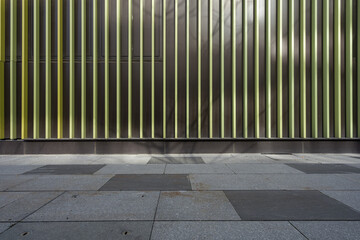 Vertical metal striped wall with gray pavement tiles in an urban street setting © zhu difeng