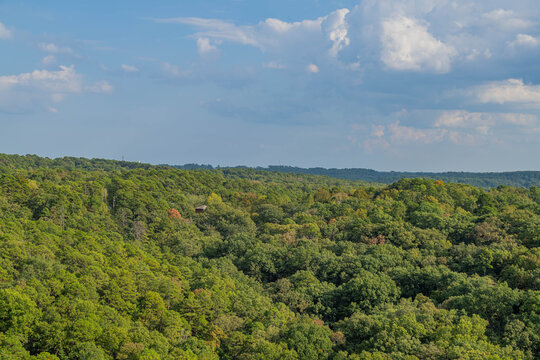 Rolling forest hills under partly cloudy sky.