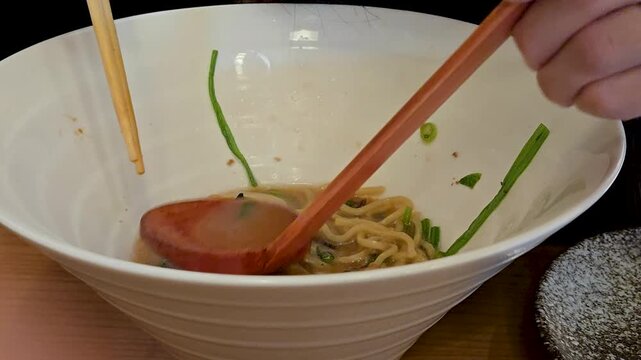 Enjoying ramen with chopsticks at a restaurant in the evening