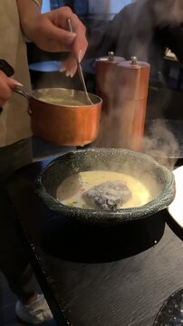 Traditional Russian cuisine. Fish soup.waitness pours the soup in a plate by securing it with a firebrand from a burning fire for much flavor and taste. High quality 4k footage