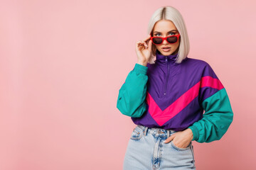 Fototapeta premium Young Blonde Woman in Retro 90s Colorblock Windbreaker Peering Over Red Sunglasses on Pink Background with Copy Space