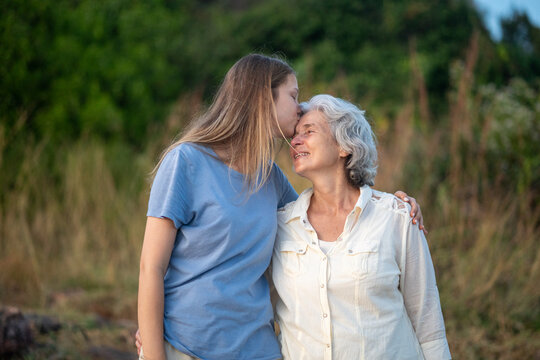 Adult daughter and senior mother sharing warm embrace while hiking outdoors smiling and enjoying time together in nature family love active lifestyle connection during trekking adventure.