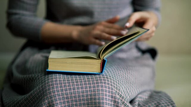 Student Holding Open and Turning Page Of Book While Reading. Learning Process at Home
