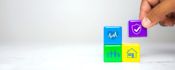 Hand placing colorful blocks with icons for health insurance and family security
