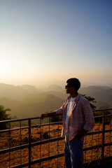 Fototapeta premium Man Gaze Serene Mountain Vista At Sunset With Warm Hues Over Landscape