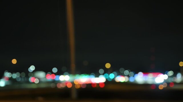 Blurred side View of car driving on a highway at night with glowing buildings. Scene shows urban transportation, night traffic. 