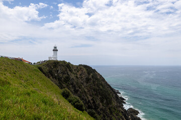 Lighthouse on dramatic coastal cliff overlooking ocean with scenic horizon and green landscape