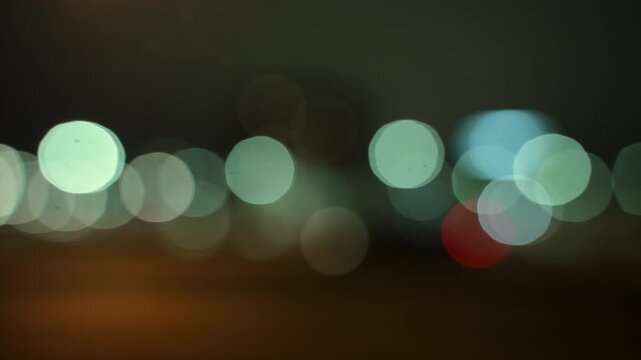 Blurred View of car driving on a highway at night with glowing buildings. Scene shows urban transportation, night traffic. 