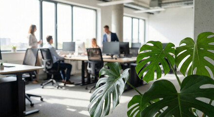 Office workers collaborating in modern workspace with green plant natural light and blurred background © Sanoor