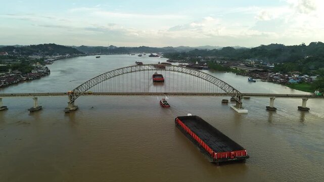 Aerial view of Mahulu Bridge (Mahakam Ulu) being passed by a coal tugboat on the Mahakam River, Samarinda