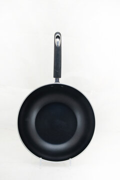 Top view of black nonstick frying pan isolated on white background, modern kitchen utensil product photography.