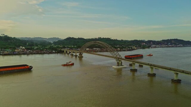 Aerial view of Mahulu Bridge (Mahakam Ulu) being passed by a coal tugboat on the Mahakam River, Samarinda