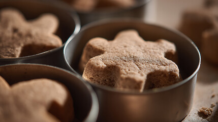 Fototapeta premium Freshly baked homemade gingerbread cookies in star and gingerbread man shapes sit in shiny metal molds, ready for holiday baking and festive treat creation
