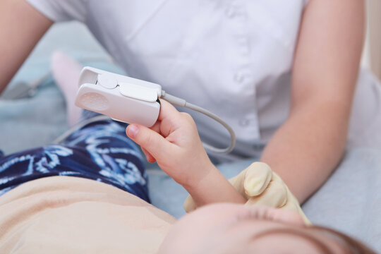 The pulse oximeter is located on the child's fingers. The child is under anesthesia before the operation. A device for measuring blood oxygen levels. The concept of modern medicine. Close-up.