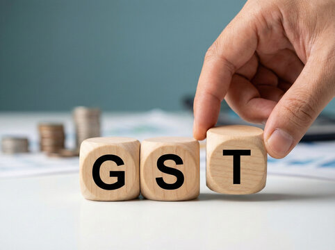 hand placing gst wooden cube blocks on a clean desk representing goods and services tax compliance accounting and business taxation concept