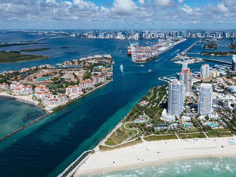 Aerial view of South Pointe Beach, Fisher Island, and Downtown Miami skyline under blue sky. c.