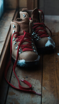 brown leather hiking boots with red laces on a wooden sauna floor
