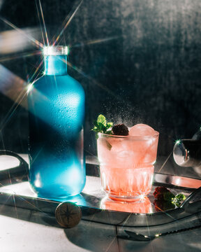 blue bottle of alcohol gin and a cocktail on a tray beautifully lit