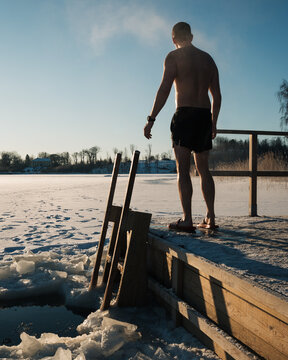 man standing on a floating sauna by the frozen baltic sea